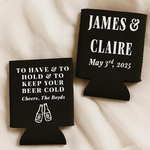 May include: Two black beer can coolers with white text. One says "TO HAVE & TO HOLD & TO KEEP YOUR BEER COLD Cheers, The Boyds" with beer bottle graphics. The other says "JAMES & CLAIRE May 3rd, 2025".