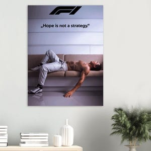 Könnte beinhalten: Ein Poster mit dem Formel-1-Logo und dem Zitat „Hoffnung ist keine Strategie“. Das Bild zeigt eine Person, die auf einem beigen Sofa liegt und eine hellgraue Hose und Turnschuhe trägt.