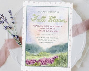 May include: A watercolor invitation with the text "Our New Home is in Full Bloom." The invitation features a landscape scene with purple flowers, green hills, and a soft, pastel sky. The invitation is on a white plate with lavender sprigs.