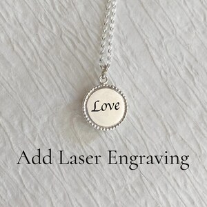 May include: A silver necklace with a round pendant that says "Love" on it. The pendant has a beaded edge.