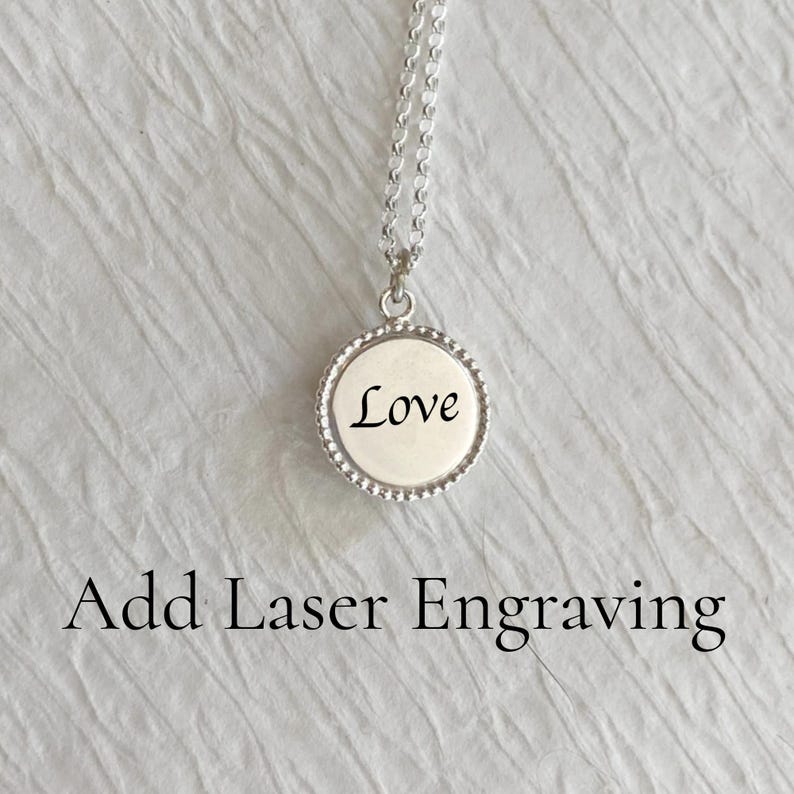 May include: A silver necklace with a round pendant that says "Love" on it. The pendant has a beaded edge.