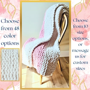 May include: A chunky knit blanket in white, pink, and off-white is draped over a wooden chair. The blanket has a thick, textured appearance. Text on the image says "Choose from 48 color options" and "Choose from 10 size options, or message us for custom sizes."