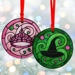 May include: Two round Christmas ornaments with red ribbons. One is pink with a crown design, the other is green with a witch hat. Both have a stained glass appearance with black outlines and decorative swirls.