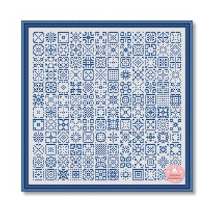 May include: A framed cross-stitch sampler with a blue border. The sampler features a grid of various geometric patterns in shades of blue on a white background. The lower right corner has a pink sticker with a bunny and the text "Stitched Sunbeams."