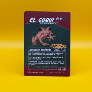 May include: A trading card featuring "El Coqui, The Gitrog Monster." The card has a brown and green background with a detailed illustration of a frog. Text includes "Legendary Creature - Frog Horror" and game instructions. The card is labeled "Unofficial Proxy Art."