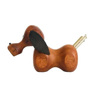 May include: Wooden dog bottle opener with a black leather ear and a silver metal opener.