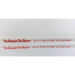 May include: Two lines of red text on a white background. The text reads "The Russian Tea Room - 150 W. 57TH ST. NYC. 212-265-0947" and "The Russian Tea Room - 150 W S7TH ST. NYC 212-265-0947".