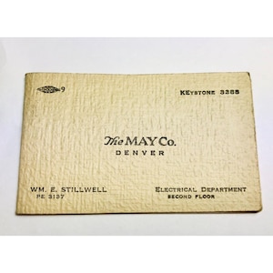 May include: A vintage cream-colored card with the text "The MAY Co. DENVER" and "WM. E. STILLWELL PE 3137". The card also includes "KEYSTONE 3388" and "ELECTRICAL DEPARTMENT SECOND FLOOR". The card has a textured surface.