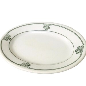 May include: White oval serving platter with a green border and floral design.