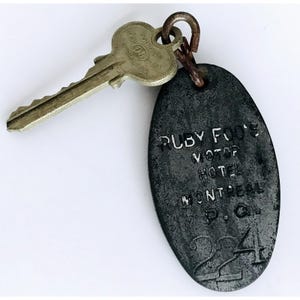 May include: A vintage metal hotel key tag with the text "Ruby Foo's Motor Hotel Montreal P.Q. 224" and a key attached.