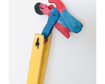 Juguete de madera vintage hecho a mano, diseño de superhéroe de arte popular artesanal.