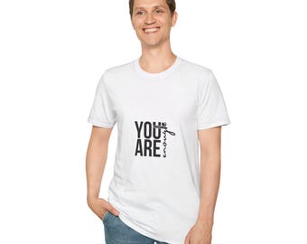 以下が含まれることがあります： 「YOU ARE enough」の黒い文字が入った白いTシャツ。Tシャツはクルーネックで、人が着ています。その人はブルージーンズを履いています。
