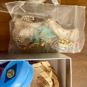 Op de afbeelding: Een doorzichtige plastic zak gevuld met verschillende sieraden, waaronder een parelketting, een turquoise en gouden hanger en een gouden ketting.