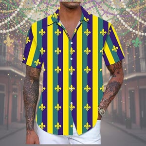 Pode incluir: Camisa de manga curta com botões e um padrão de listras verticais em amarelo, verde e roxo. A camisa apresenta um design de flor-de-lis e uma gola clássica.