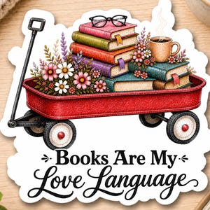 May include: A red wagon filled with a stack of colorful books, a pair of black glasses, a steaming mug, and various flowers. The text below the wagon reads, "Books Are My Love Language." The sticker has a white border and a die-cut shape.