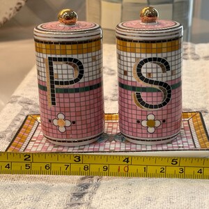 Puede incluir: Un juego de salero y pimentero de cer&aacute;mica con dise&ntilde;o de mosaico rosa, dorado y blanco. Los saleros y pimenteros tienen tapas doradas y est&aacute;n etiquetados con las letras "P" y "S". El juego se encuentra sobre una bandeja a juego.