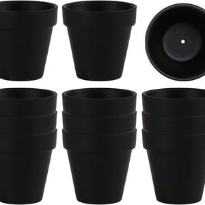 May include: A set of matte black plant pots with a tapered shape and a wide rim. The collection includes individual pots shown from the side and a top-down view revealing a drainage hole at the base. These containers are uniform in color and design.