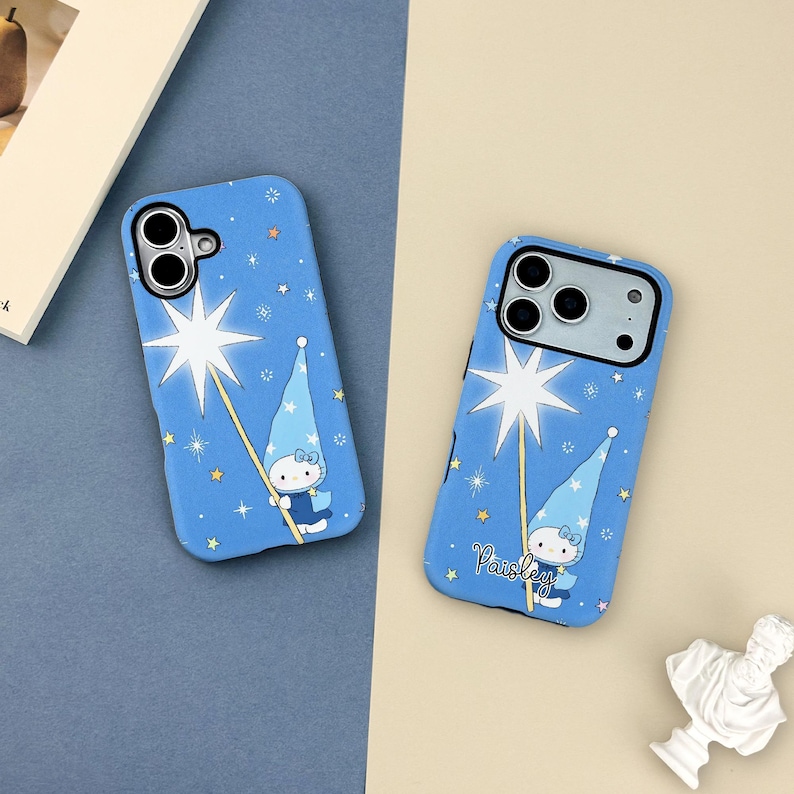 May include: Two blue phone cases with a whimsical design. Each case features a cartoon character holding a star wand, surrounded by stars. The word "Paisley" is written on one case.