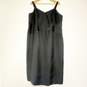 Pode incluir: Um vestido preto sem mangas com decote em V e silhueta ajustada. O vestido tem um design simples com uma bainha reta.