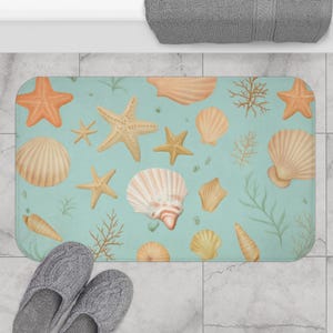 May include: A rectangular bath mat featuring a sea-themed design. The mat has a light blue background with illustrations of seashells, starfish, and seaweed in shades of beige and orange. Gray slippers are in the foreground.
