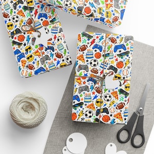 Peut inclure: Papier cadeau avec un motif coloré de manettes de jeu vidéo, skateboards, ballons de football, ballons de rugby, parts de pizza, gâteaux d'anniversaire, éclairs et visages souriants jaunes, noué avec de la ficelle brune et des étiquettes blanches.