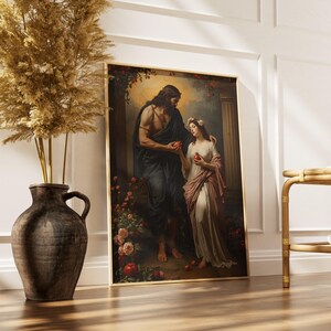 May include: A framed art print shows a classical scene of two figures, a man and a woman, in a garden. The man, in dark fabric, offers a red fruit to the woman, who wears a white gown and floral crown. The artwork is in a gold frame.