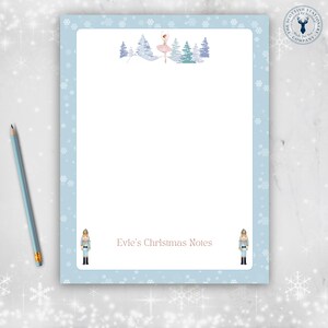 May include: Light blue stationery with a snowflake border and a ballerina illustration. The top features a ballerina in a pink dress and winter trees. The bottom has the text "Evie's Christmas Notes" and two toy soldier illustrations.