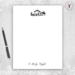 May include: White stationery with a black illustration of the Nativity scene at the top. The text "© Holy Night" is at the bottom. A black pen is on the left side of the stationery. The Scottish Stationery Company logo is in the upper right corner.