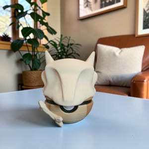 May include: A Cubone-themed figurine, featuring a bone-white skull and a tan body. The figurine has a detailed design, with a bone accessory. The product is sitting on a light blue surface. The Pokeforge3D logo is visible.
