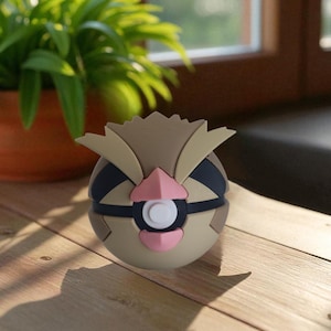 May include: A detailed, spherical figurine of a cartoon owl-like creature, featuring tan, brown, black, and pink accents. The figure has a white circular detail in the center and is set on a wooden surface, with a potted plant in the background.