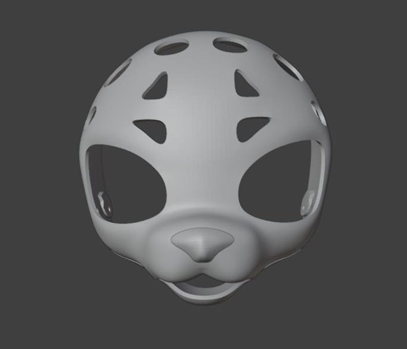 Op de afbeelding: Een lichtgrijze, 3D-geproduceerde masker in de vorm van een gestileerd dierengezicht. Het masker heeft grote oogopeningen, een prominente neus en een mondopening. Het heeft verschillende cirkelvormige en driehoekige uitsparingen aan de boven- en zijkanten.