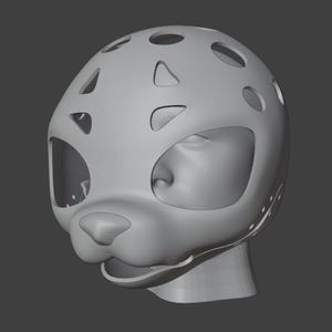 Op de afbeelding: Een grijze, 3D-geprinte masker met een katachtig ontwerp. Het masker heeft grote oogopeningen, een neus en een mond, met verschillende cirkelvormige en onregelmatig gevormde uitsparingen aan de bovenkant. De algemene vorm suggereert een gestileerde dierenkop.
