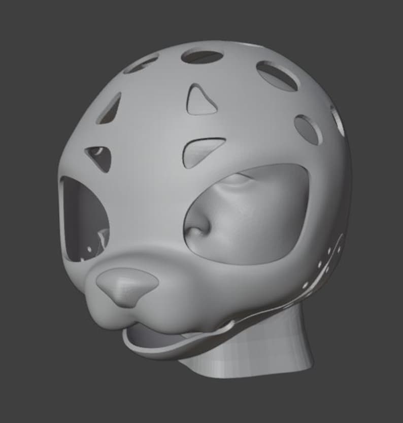 Op de afbeelding: Een grijze, 3D-geprinte masker met een katachtig ontwerp. Het masker heeft grote oogopeningen, een neus en een mond, met verschillende cirkelvormige en onregelmatig gevormde uitsparingen aan de bovenkant. De algemene vorm suggereert een gestileerde dierenkop.