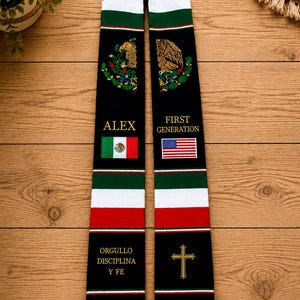 Pode incluir: Estola de formatura preta com detalhes das bandeiras mexicana e americana. Apresenta o nome "ALEX", as palavras "FIRST GENERATION" e a frase "ORGULLO DISCIPLINA Y FE". Inclui uma cruz dourada e um brasão mexicano.