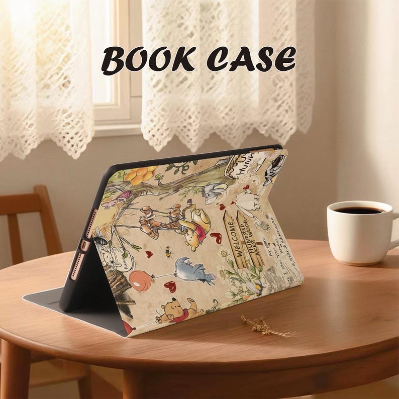 May include: A tablet case with a colorful Winnie the Pooh design, featuring characters and scenes from the Hundred Acre Wood. The case is open and propped up on a wooden table, with the words "BOOK CASE" printed at the top.