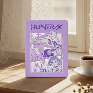 May include: A lavender-colored notebook featuring the text "HUNTR/X" at the top. The notebook's cover displays a comic-style illustration of three anime-style characters. The characters are in a purple and white color scheme.