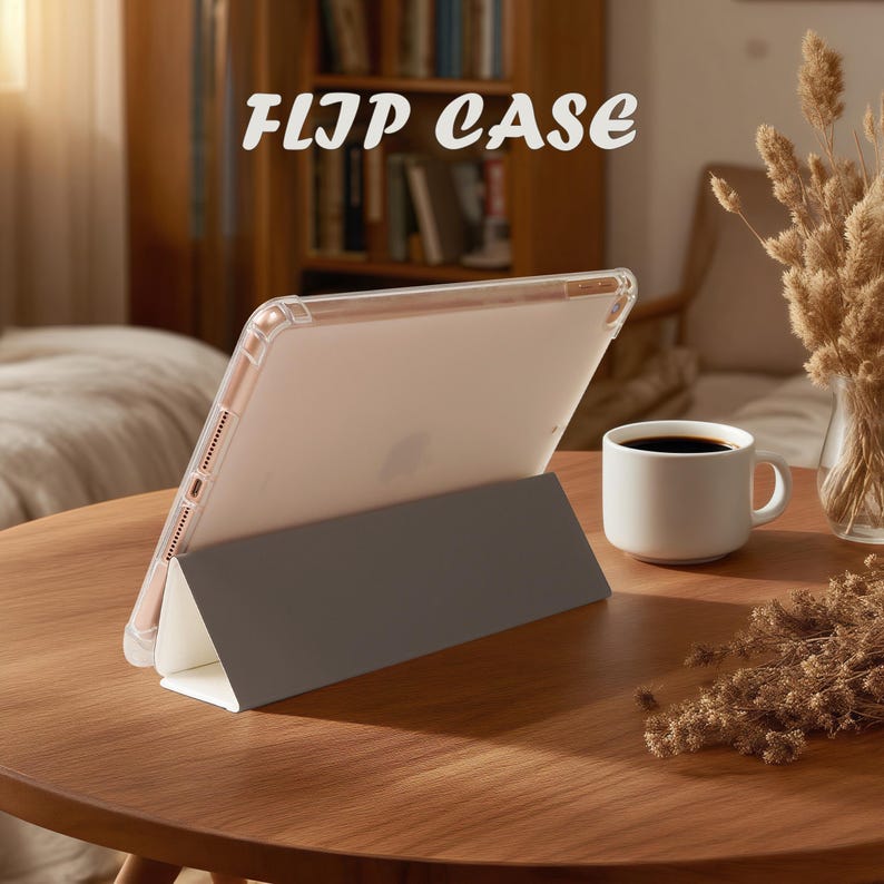 May include: A clear flip case for a tablet, propped up on a gray stand. The text "FLIP CASE" is displayed in a stylized font. A white mug of coffee sits on a wooden table, with dried flowers in the background.