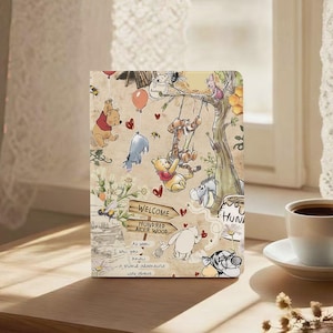May include: A beige tablet case with a charming illustration of Winnie the Pooh and his friends. The design includes Pooh, Tigger, Eeyore, and Piglet, with a sign reading "Welcome Hundred Acre Wood". The case has a vintage, storybook aesthetic.