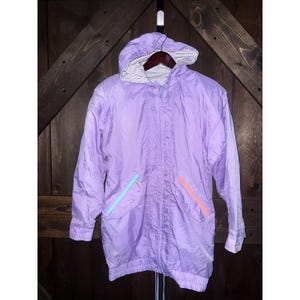 May include: A light purple hooded jacket with a drawstring waist and two front pockets. The jacket has a zipper closure and a striped lining in the hood. The pocket trim is light blue and coral.