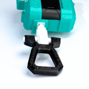 May include: A teal and black toy launcher with the text "LONG RIPCORD GRIP". The launcher has a white pull cord and a black grip. The launcher is designed for a toy.