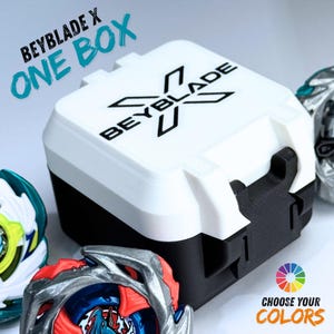 Può includere: Una Beyblade X One Box bianca e nera con il logo Beyblade. La scatola è circondata da Beyblade colorati. Il testo sulla scatola dice "SCEGLI I TUOI COLORI".