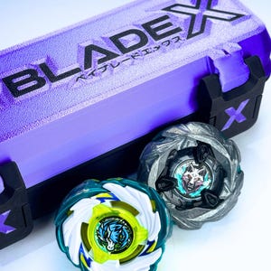 Könnte beinhalten: Eine lila-schwarze Blade X Aufbewahrungsbox mit zwei Kreisel. Einer ist türkis, weiß und gelb mit einem Drachenmotiv. Der andere ist grau mit einem Wolfsmotiv. Die Box hat den Text "BLADEX" und japanischen Text.
