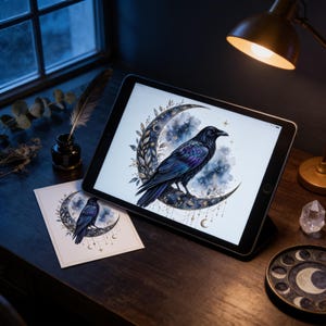 a tablet displaying a digital illustration of a black crow perched on a crescent moon, surrounded by stars and other celestial elements. The tablet is placed on a wooden desk, with a lamp and other decorative items visible in the background.