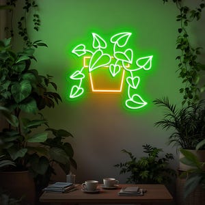 May include: A neon sign depicting a potted plant with vibrant green leaves and a yellow pot. The sign is mounted on a green wall, surrounded by potted plants. A wooden table with cups and books is in the foreground.
