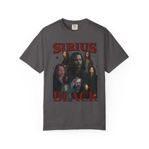 May include: Dark gray t-shirt featuring a collage of images and the words "SIRIUS BLACK" in red. The shirt has a vintage, retro style, with a crew neck and short sleeves. The design includes multiple images of a man.