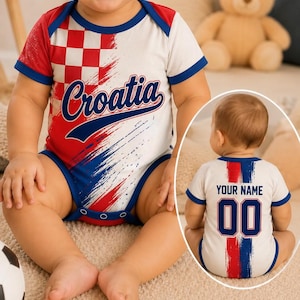 May include: A short-sleeved baby bodysuit featuring a red and white checkered pattern on the front with the text Croatia in blue. The back displays the text Your Name above the number 00, accented by red and blue brushstroke graphic details.