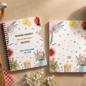 May include: Two spiral-bound notebooks with a white cover featuring watercolor illustrations of lemons, berries, flowers, and kitchen items. The text reads: WAYNE FAMILY THE "NOT-SO-PERFECT" RECIPES OUR LITTLE BOOK OF YUMS in dark brown and blue.