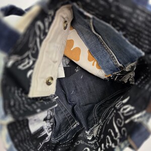 May include: A denim tote bag with a patchwork design. The bag features a mix of blue denim, patterned fabric, and a cream-colored interior with a yellow clover pattern. The bag has a handle and is constructed with visible stitching and metal button closures.