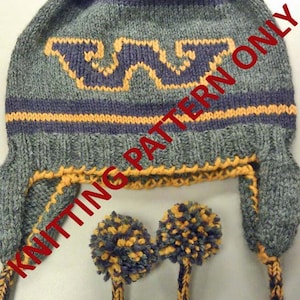 May include: Gray knitted hat with a purple and orange pom-pom on top. The hat has a purple and orange striped band and a purple and orange logo on the front. The hat has ear flaps with pom-poms on the ends.