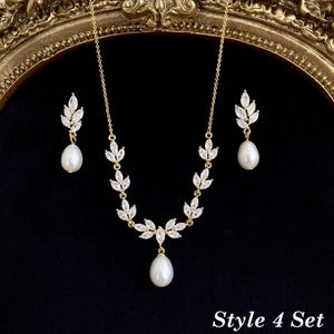 May include: A gold-toned necklace and earring set featuring white teardrop pearls and marquise-cut clear crystals arranged in a leaf-like pattern. The necklace has a central pearl drop, and the earrings feature matching pearl drops. Text reads Style 4 Set.
